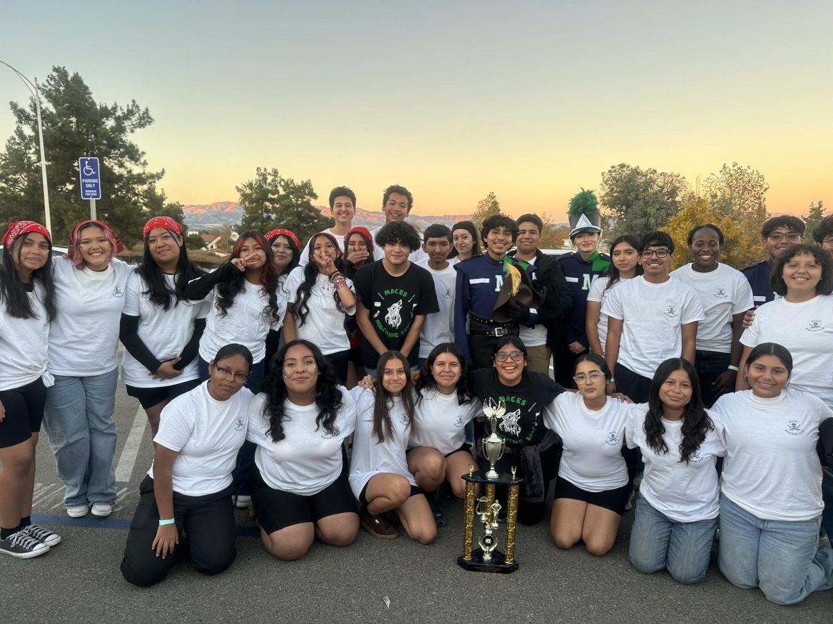 TROPHY IN HAND, SPIRITS HIGH - The marching band celebrates their achievement. Posed in two rows with their trophy on the ground, the band and color guard proudly show off their hard-earned achievement. "After our performance, I felt accomplished and very emotional. Crying together with years of joy, happiness, and accomplishment." said Mota