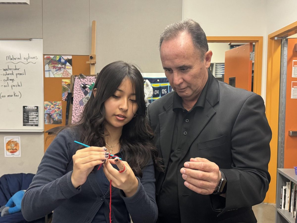 THREADING THE HOOK - At the final meeting of the semester, Emely Cardenas, President of the Crochet Club, teaches MACES Principal Gabriel Duran how to crochet in Ms. Hanson's room (4-101).