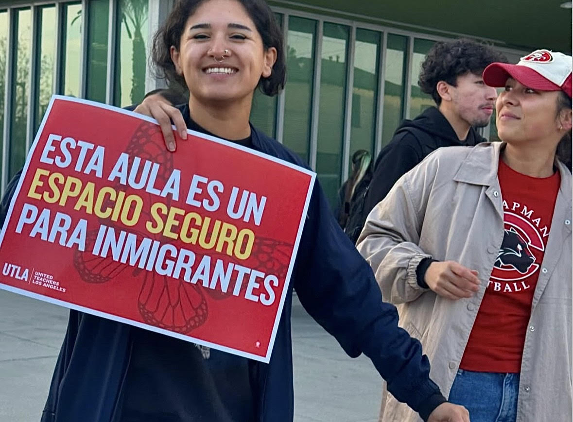 A SIGN OF SUPPORT - Nora Torres, an AP English Literature teacher, holds up a sign outside of MACES on January 28, to remind students that the school is a safe place for immigrants. The message was shared during the morning, reinforcing the school's commitment to inclusivity and support for all students.