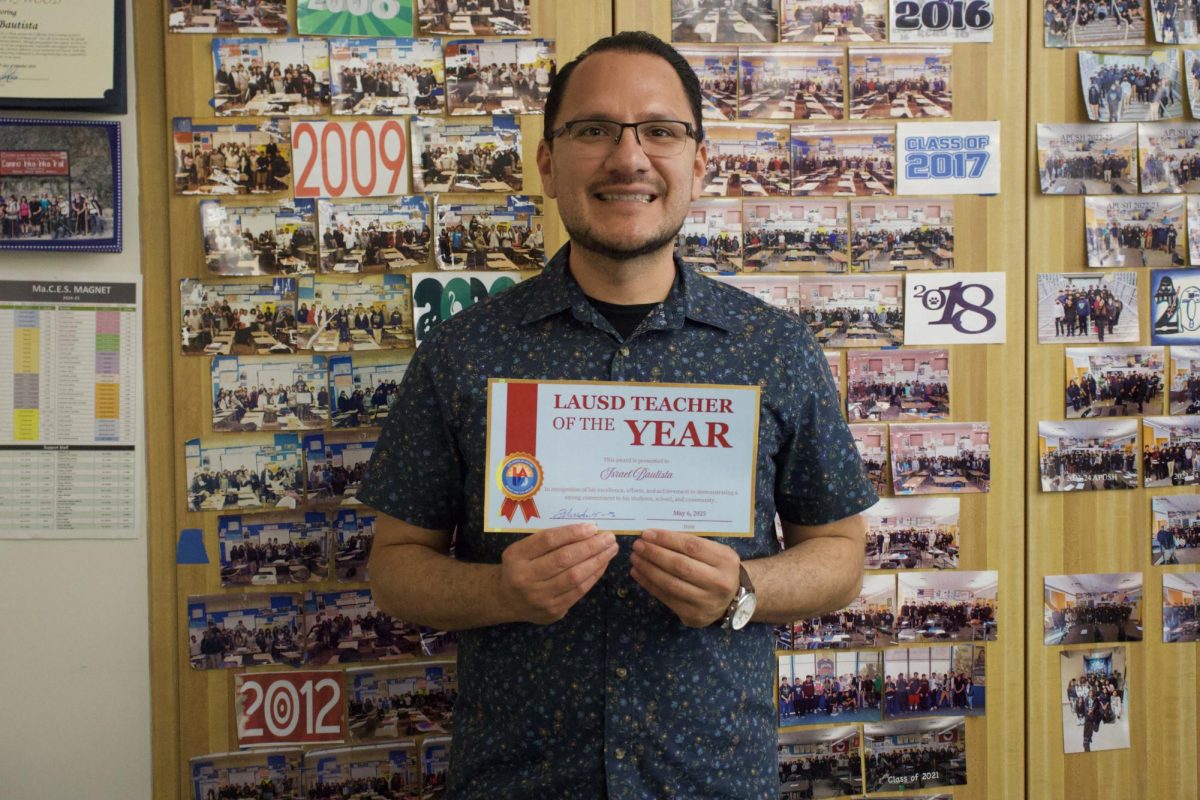 BRAINS, BATTLES, AND BIG WINS - Mr. Bautista holds up a certificate of recognition presented by the school in front of a variety of memorable photographs of his former classes for receiving the award of Teacher of the Year.