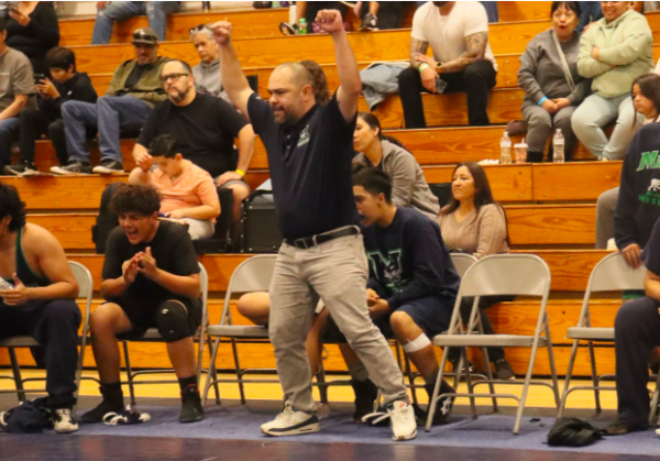 SUCCES - The wrestling coach observes from the gym as one of his athletes competes in a boys’ match at El Rancho High School where the wrestler went on to win the match.